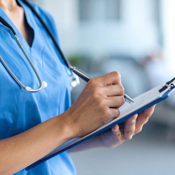 Close up of a nurse writing on a clip board