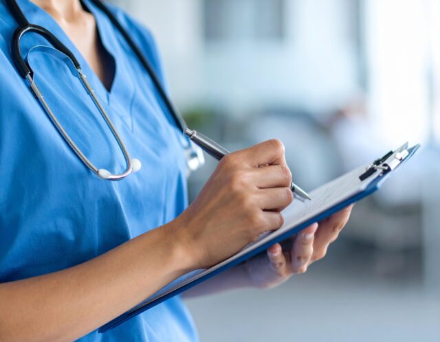 Close up of a nurse writing on a clip board