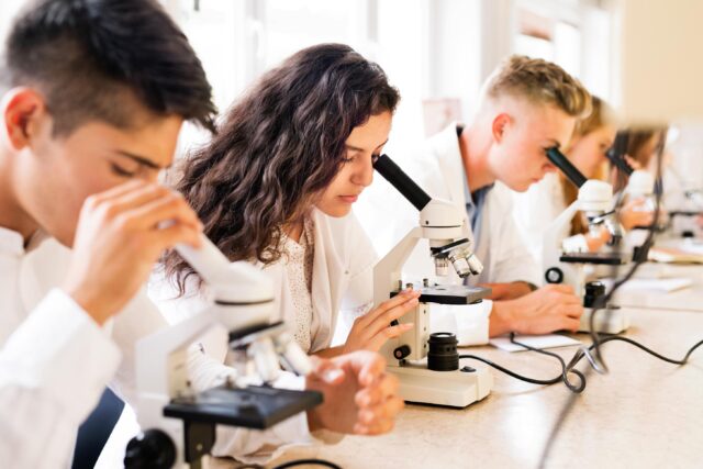 science students with microscopes in laboratory
