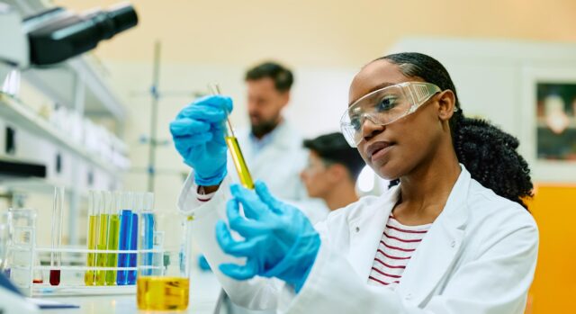 Chemistry student working in laboratory holding test tubes