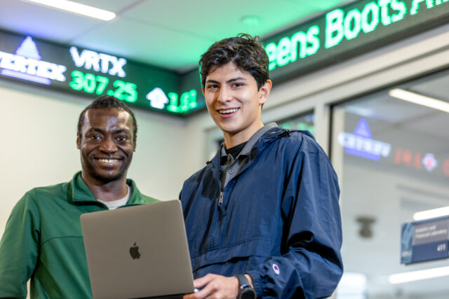 Two Students from Mercy at the Stock Exchange holding a laptop