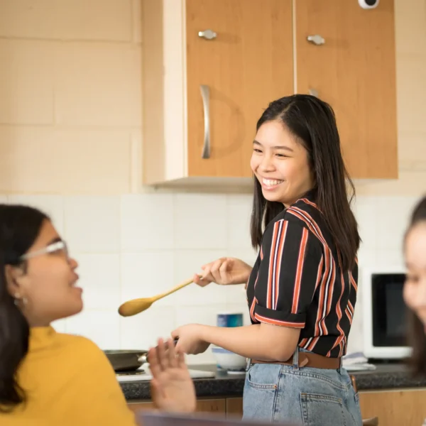Smiling students preparing food together in shared student housing