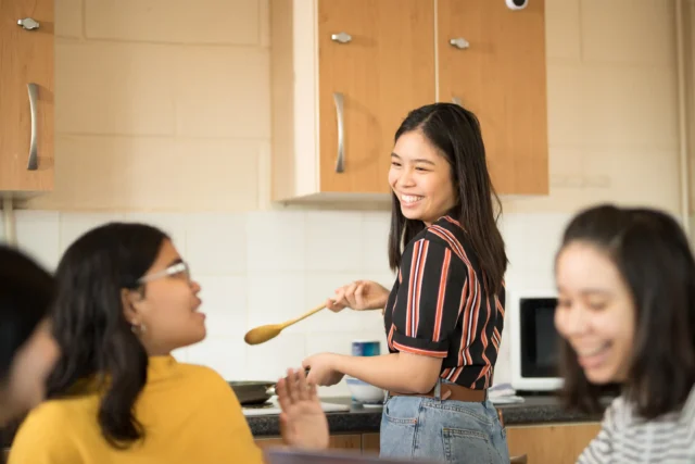 Smiling students preparing food together in shared student housing