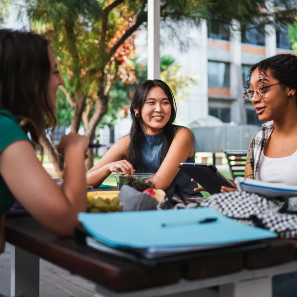 Group of three students sitting outside talking